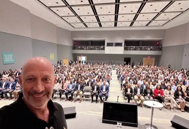 Chris Daigle on stage in front of a packed auditorium at a Scaling Up event